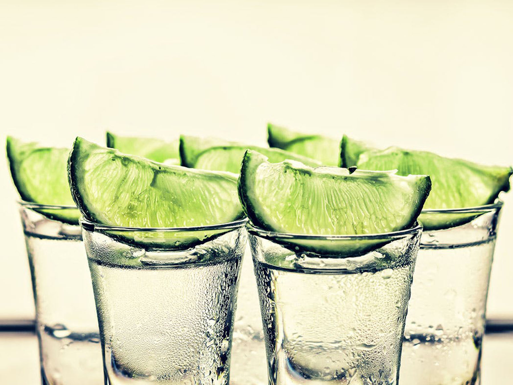 clear shot glasses with tequila and lime